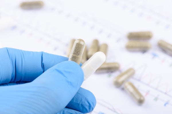Gloved hand holding capsules from a custom supplement manufacturer